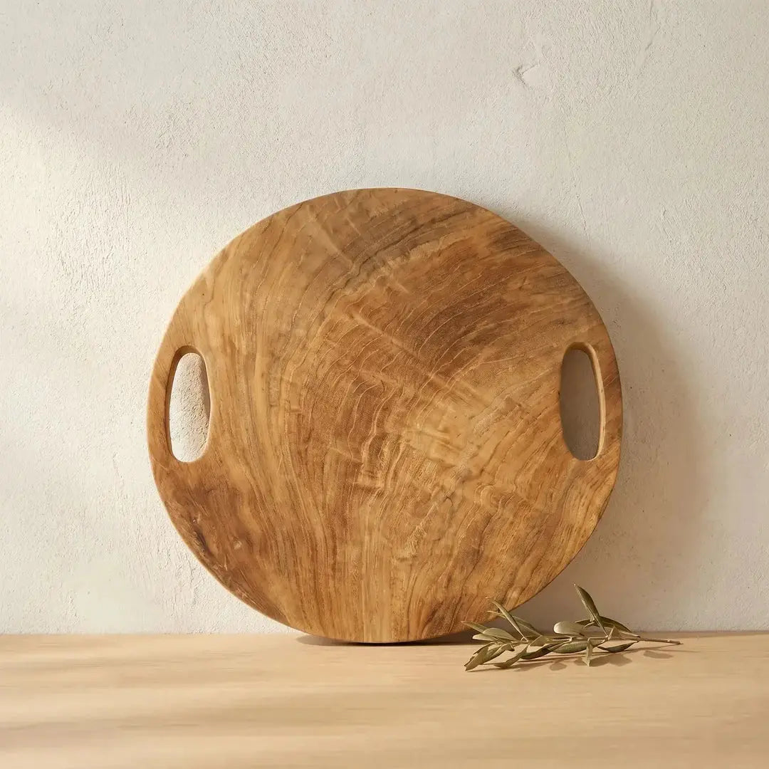 Δίσκος Teak Root από μασίφ ξύλο τικ σε κάθετη διακοσμητική τοποθέτηση σε πάγκο κουζίνας με κλαδί ελιάς