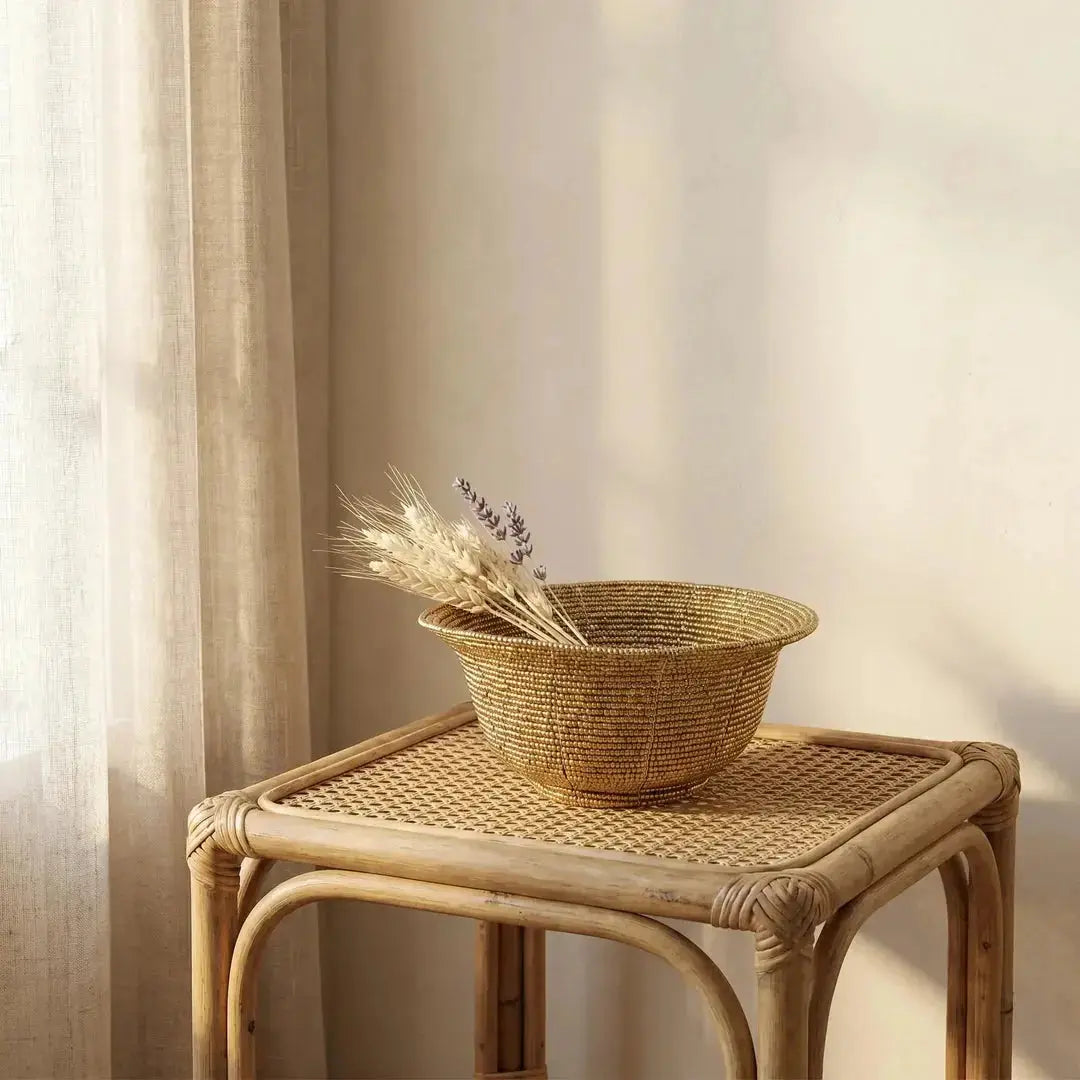 Καλάθι Beaded με χρυσές χάντρες σε τραπέζι από ρατάν δίπλα σε λινή κουρτίνα με αποξηραμένα στάχυα