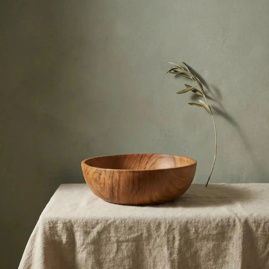 Μπολ Teak Root από ξύλο τικ με rustic υφή σε πάγκο με λινό και τοίχο sage με κλαδί ελιάς
