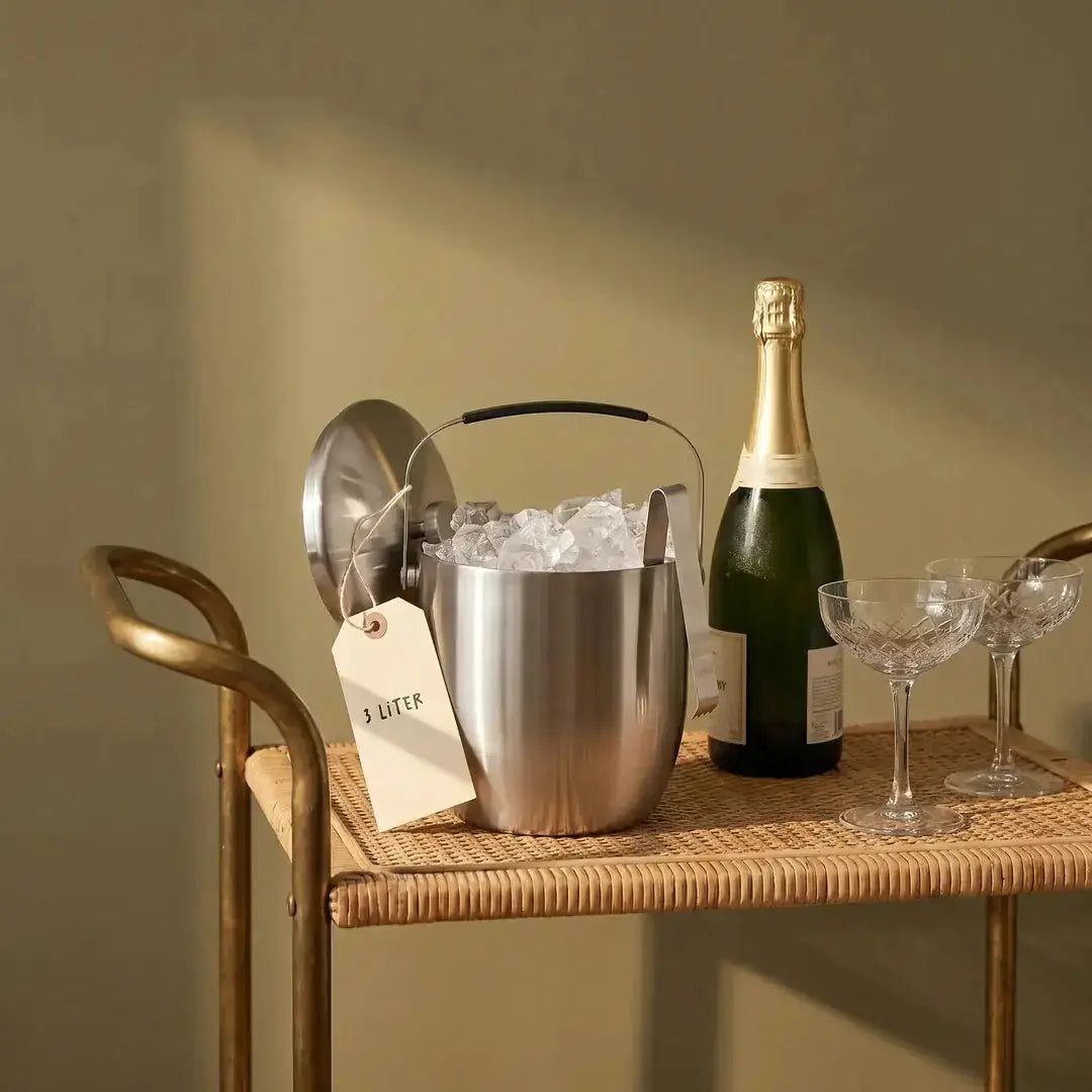 Παγοθήκη από ανοξείδωτο ατσάλι σε vintage bar cart με μπουκάλι σαμπάνιας και κρυστάλλινα coupe ποτήρια