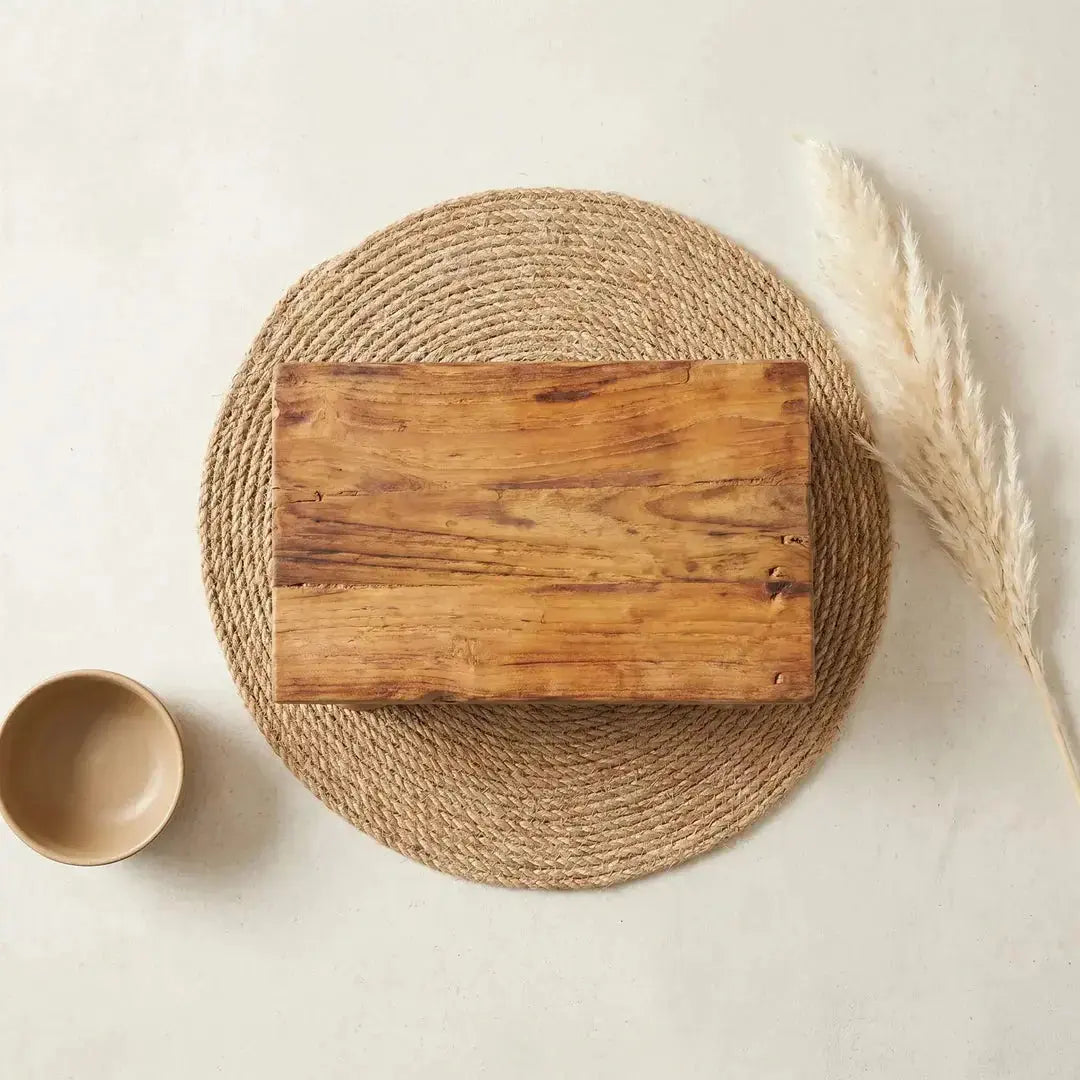 Ξύλινη βάση παρουσίασης Teak top-down σε πλεκτό σουβερ από γιούτα σε τσιμεντόγια επιφάνεια με κεραμικό μπολ και pampas grass