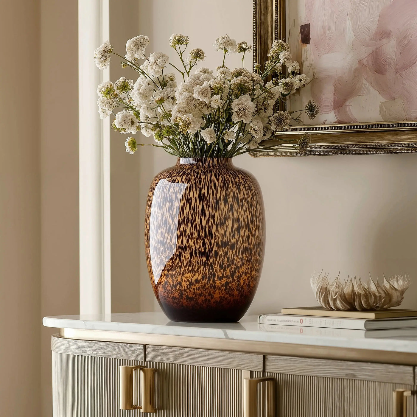 Γυάλινο βάζο Cheetah σε console table με λευκά αγριολούλουδα και χρυσή κορνίζα - Phos & Gaia