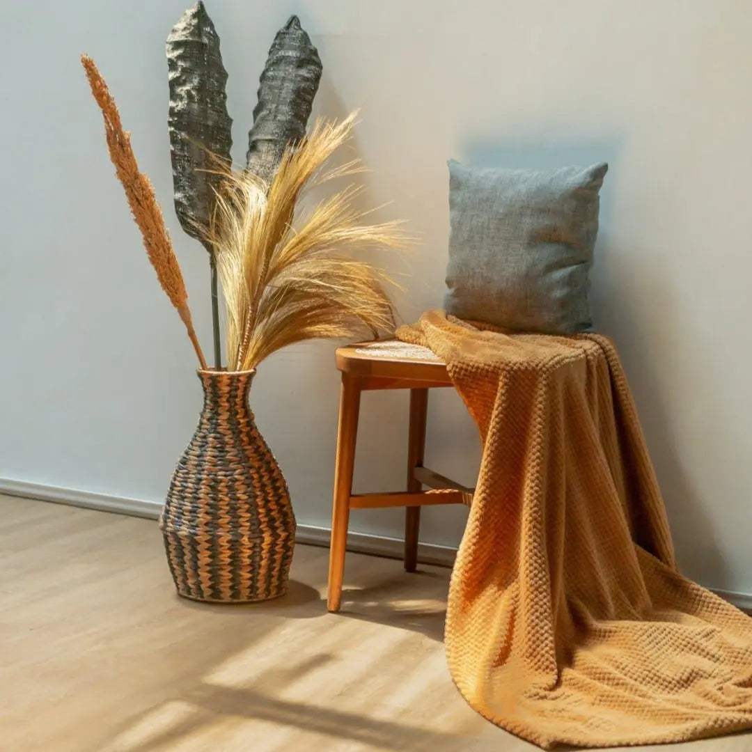Το βάζο Dayana με pampas grass στο πάτωμα δίπλα σε ξύλινο σκαμπό με ριχτάρι